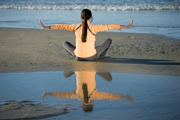 坐在沙滩上练瑜珈的美女图片