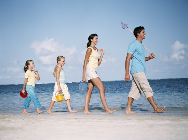 拿着鱼具走在沙滩上的一家人图片