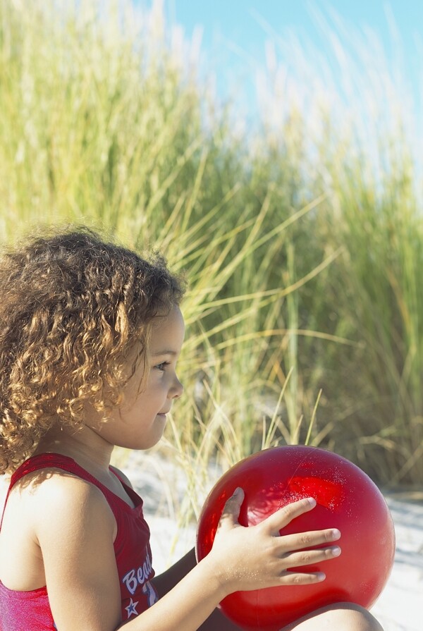 沙滩上手拿球的小女孩图片