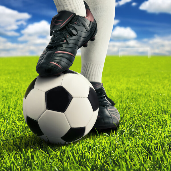 草地上脚踩在足球上的运动员