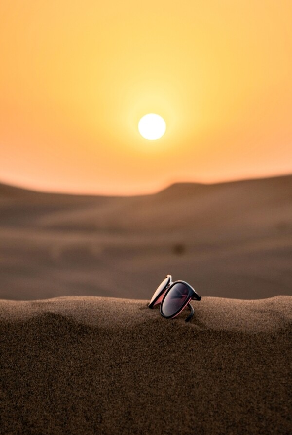 夕阳下放到沙子上的墨镜